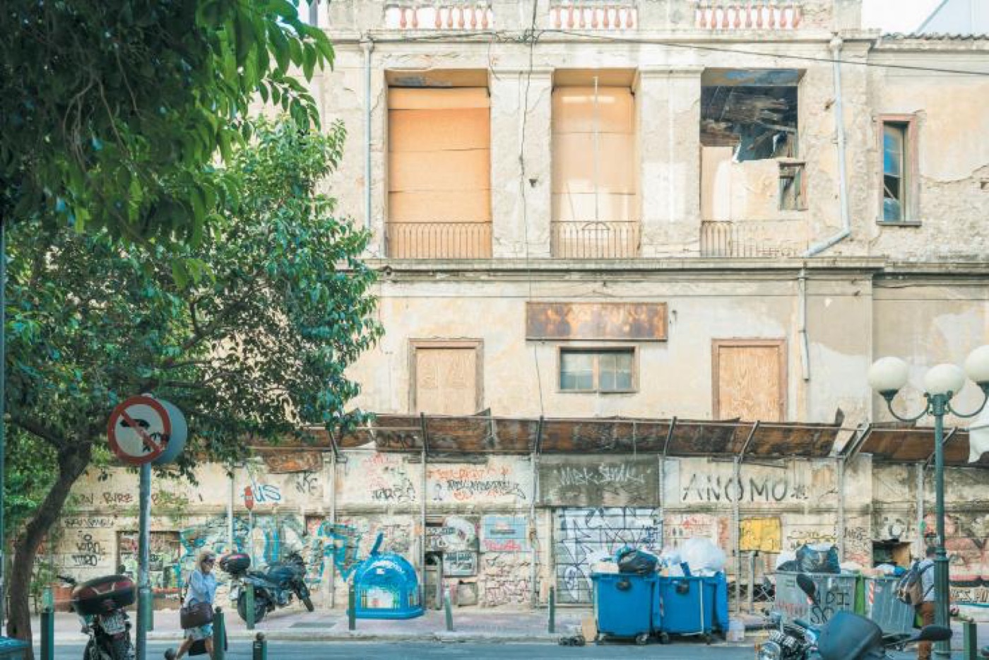 A derelict building with graffiti and rubbish bins in central Athens